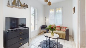 Una sala de estar moderna con un televisor de pantalla plana, un aparador negro, una mesa de centro redonda, un sofá y una obra de arte decorativa con forma de velero.