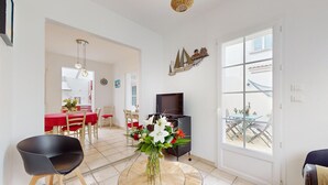 Una sala de estar moderna con comedor, televisor y un ventanal grande.