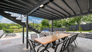 Un área de comedor al aire libre cubierta con piscina, sillas y una mesa.