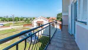 A balcony with a view of a residential area, a car parked on the street, and a building with a tiled roof. - Lovely home in Benkovac (Benkovac)