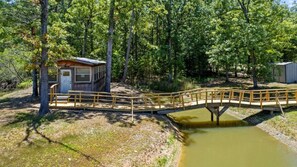 Cross a serene bridge to a secluded haven, surrounded by lush trees and a tranquil water body.