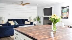 Een moderne woonkamer met een houten eettafel, een blauwe bank en een witte kast.