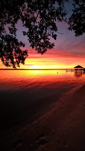 A beach at sunset with a wooden structure on the shore.