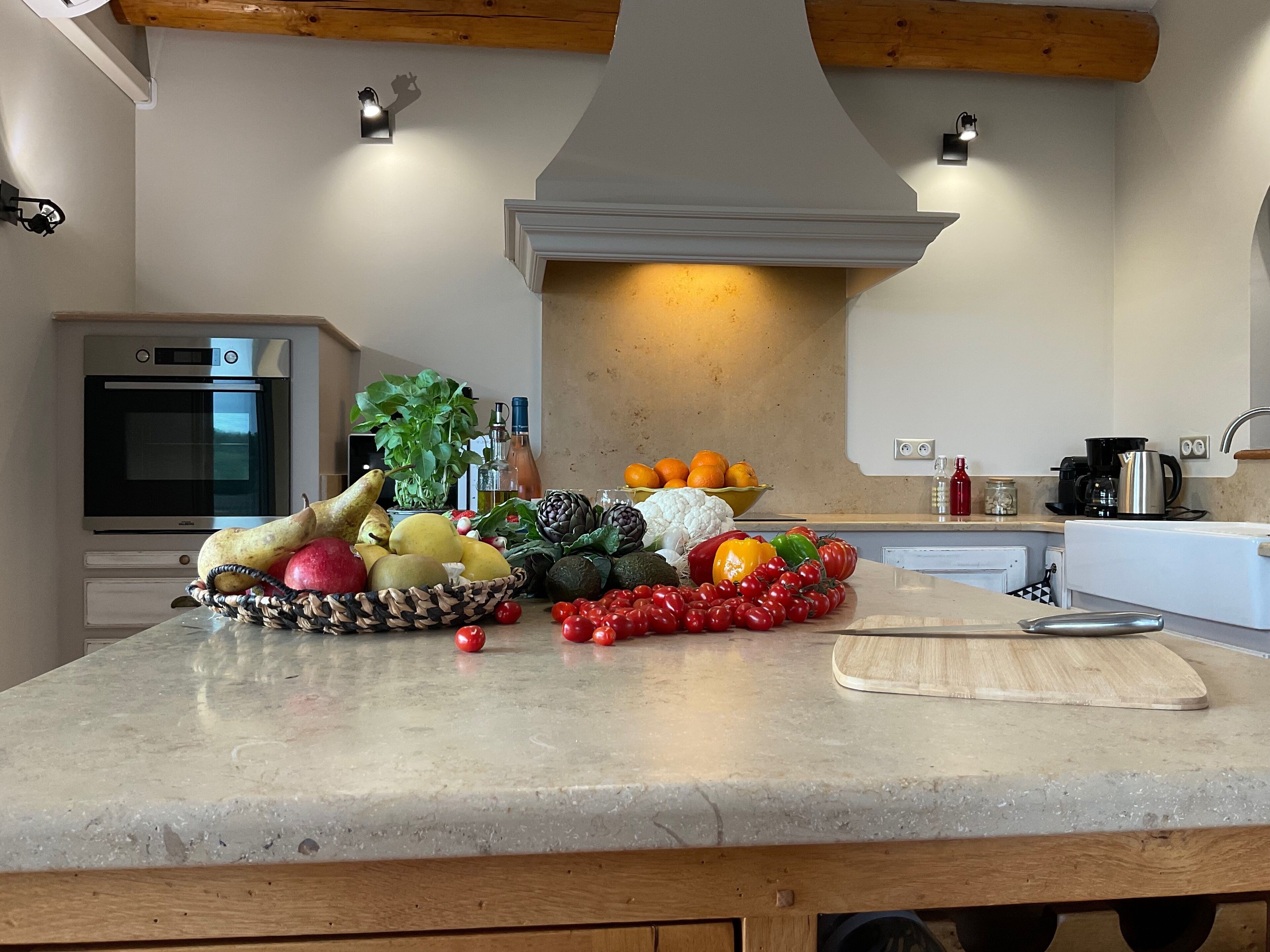 Una encimera de cocina con frutas y verduras frescas, una tabla de cortar y una cafetera.