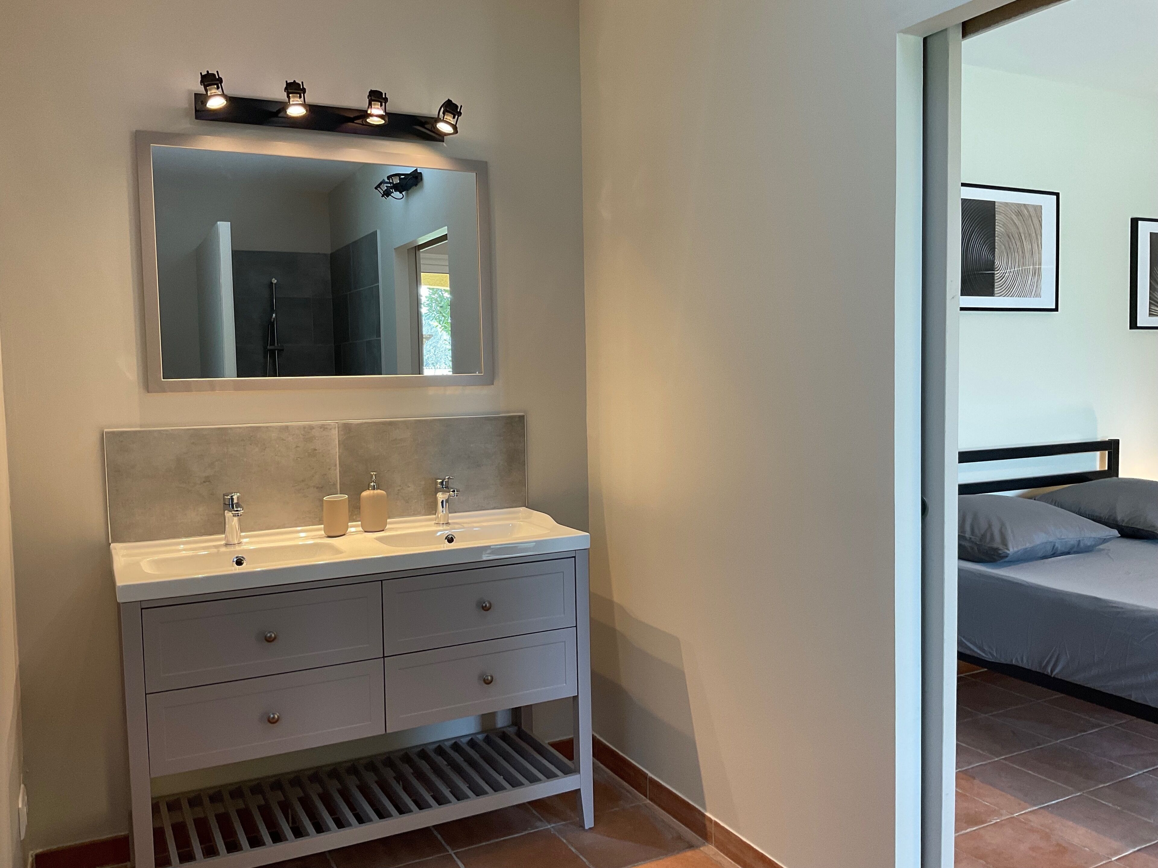 A bathroom with a white vanity, a mirror, and a light fixture above it.