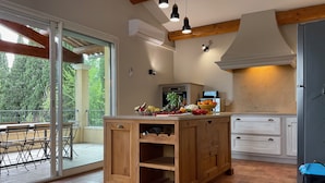Una cucina con isola in legno, mobili bianchi e vista all'esterno.