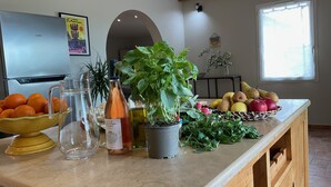 Un piano di lavoro in cucina con diversi tipi di frutta, una bottiglia di vino e piante in vaso.