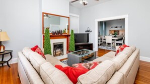 A living room with a sofa, a coffee table, a fireplace, a television, and a ceiling fan. - Luxury 4BR|KING|Epic Backyard|HOT TUB|Fire Pit (Louisville)