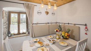 Ein gemütlicher Essbereich mit Tisch für zwei Personen, ausgestattet mit karierter Tischdecke, Tellern mit Essen und einer Obstschale.