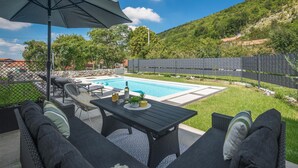 Ein Garten mit Swimmingpool, Gartenmöbeln und Blick auf eine hügelige Landschaft.