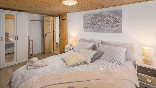 Ein Schlafzimmer mit Bett, Nachttischen, einem Kleiderschrank und einem Bild an der Wand.