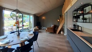 A modern kitchen with a dining area, large windows, and a staircase leading to an upper level.