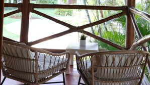 Un espace extérieur abrité, aménagé avec des chaises en osier et un luminaire suspendu.