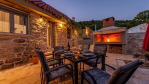 An outdoor dining area with stone walls, a brick oven, and wicker chairs. - Gorgeous home in Bruska with private swimming pool, can be inside or outside (Bruska)