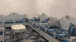 Una habitación con dos sofás grises tapizados, cojines estampados, una mesita blanca y una araña.