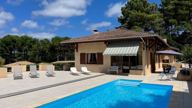 A two-story house with a swimming pool, outdoor seating, and a covered patio.