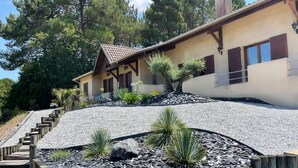 A house with a sloped roof, wooden deck, and a gravel garden with rocks and plants.