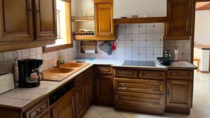 A kitchen with wooden cabinets, a tiled backsplash, a built-in oven, and a coffee maker.
