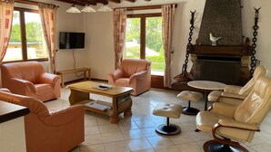 A spacious living room with leather sofas, a coffee table, and a fireplace.