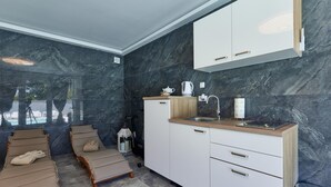 A modern kitchen with marble walls, a wooden countertop, and white cabinetry. - Awesome home in Kapela with sauna (Kapela)