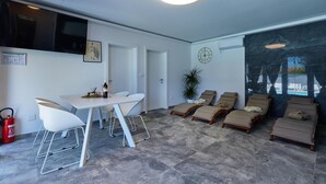 A modern room with a dining area, lounge chairs, and a large window with a view. - Awesome home in Kapela with sauna (Kapela)