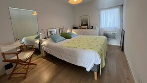 A bedroom with a bed, bedside tables, a chair, a mirror, a window, and a ceiling light. - CARNAC - Apartment 2 rooms - 4/5 persons - Terrace Sea View (CARNAC)