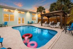 A swimming pool with lounge chairs and a wooden pergola.