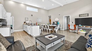 Una sala de estar moderna con comedor, cocina y un televisor de pantalla plana grande.