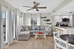 A modern living room with a sectional sofa, a glass coffee table, and a ceiling fan.