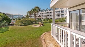 A hotel courtyard with a well-maintained lawn, a seating area, and a pool. - Gulf Shores Plantation-West 1154 (Gulf Shores)