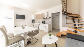 Um apartamento moderno com área de jantar, cozinha e escada com design em madeira.