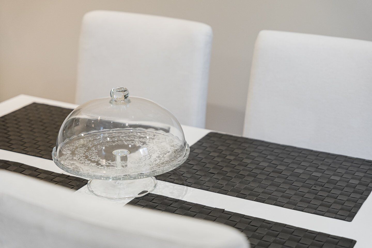 A clear glass dome centerpiece on a table with a black and white checkered placemat.