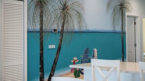 Een kamer met een strandmuur, een witte deur en een tafel met stoelen.