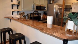A kitchen with a wooden countertop, black stools, and stainless steel appliances.