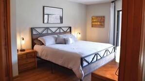A bedroom with a bed, bedside tables, a framed picture on the wall, and a motivational quote.