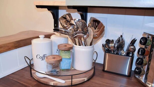 A kitchen counter with a coffee station, including a coffee maker, jars, and utensils.
