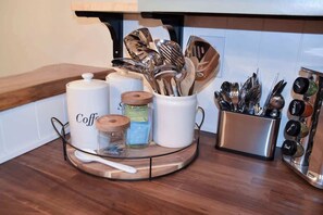 Eine Küchenarbeitsplatte mit einer Kaffeestation, inklusive Kaffeemaschine, Gläsern und Küchenutensilien.