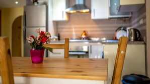 A modern kitchen with white cabinets, a stainless steel range hood, and a wooden dining table with a pink vase of flowers. - Modern & Large Studio in Casablanca - Bd Anfa (Casablanca)