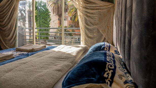 A bed with a blue and white patterned blanket, a beige throw, and a folded towel. - Modern & Large Studio in Casablanca - Bd Anfa (Casablanca)