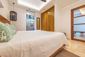 A bedroom with a bed, a wooden wardrobe, a ceiling fan, and a view through a glass door. - Casa Selva Ocean View Luxury Home- 4 Bedroom (Puntarenas Province)