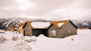 Een woonwijk met huizen onder een sneeuwdek, een garage en een buitenkraan.