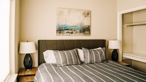 Een hotelkamer met een groot bed, twee nachtkastjes met lampen, een schilderij aan de muur en een raam.