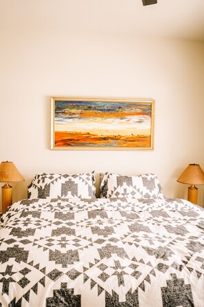 Ein Schlafzimmer mit einem Bett, zwei Lampen und einem Bild an der Wand.