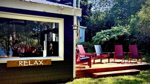 Een klein gebouw met een 'RELAX'-bord, een raam en een terras met stoelen.