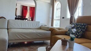 Un salon avec un canapé, une petite table et un luminaire décoratif au plafond.