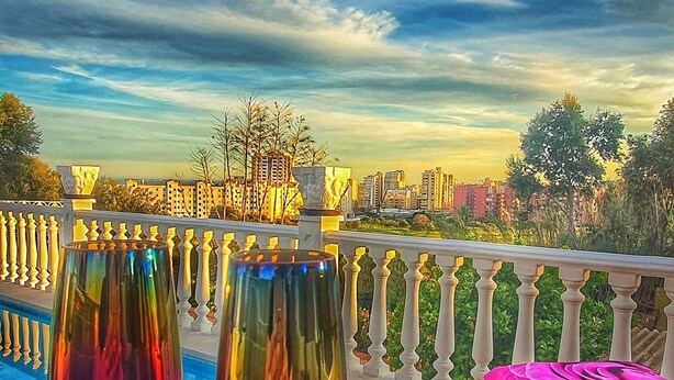 Deux verres à vin posés sur un sol en terrazzo, avec une vue sur le paysage urbain en arrière-plan.