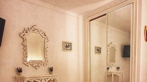 Une chambre à coucher avec un grand lit, une coiffeuse avec un miroir, une commode et un grand miroir mural.