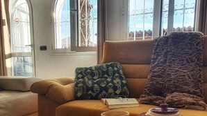 Un salon chaleureux avec un canapé, une table basse et une vue à travers de grandes fenêtres en arc de cercle.