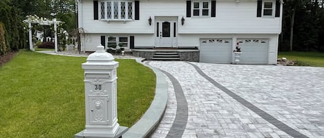 Une maison à deux étages avec une boîte aux lettres en pierre, une allée et un garage.