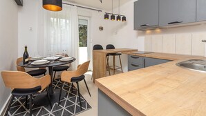 A modern kitchen with a wooden island, grey cabinets, and a dining area with a round table and chairs. - 1 bedroom nice apartment in Pula (Pula)